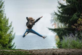 Eine Frau springt in die Luft in einem Wald.