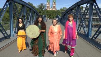 Vier bunt gekleidete Frauen auf der Blauen Brücke