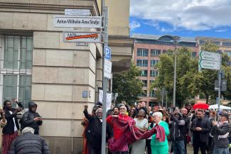 Straßenansicht mit neuem Straßenschilder Anton Wilhelm Amo Straße in Berlin und mit jubelnden Schwarzen Aktivist:innen